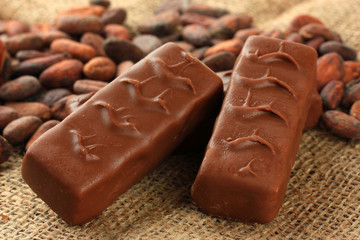 Delicious chocolate bars with cocoa beans close up