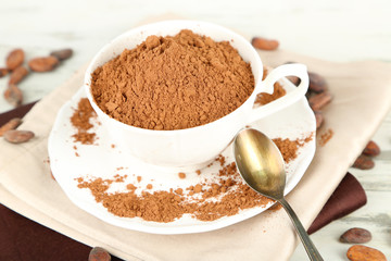 Cocoa powder in cup on napkin on wooden table