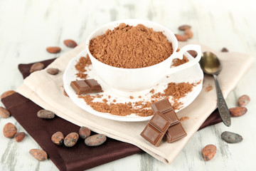 Cocoa powder in cup on napkin on wooden table