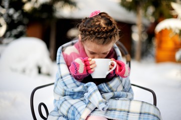 Child girl with a cup of hot tea outdoors