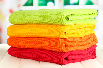 Colorful towels on wooden table on window background