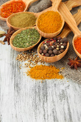 Assortment of spices in wooden spoons on wooden background