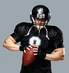 American football player with ball wearing helmet and jersey