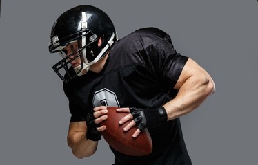 American football player with ball wearing helmet and jersey