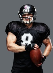 Fototapeta premium American football player with ball wearing helmet and jersey