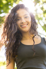 Casual cheerful brunette standing on grass in sunlight