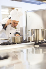 Concentrating head chef tasting food from ladle