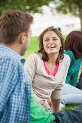 Obraz premium Casual happy students sitting on the grass chatting