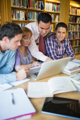 Mature students with teacher and laptop in library