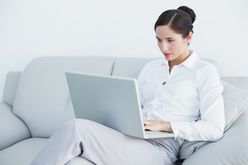 Well dressed woman using laptop on sofa