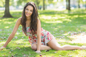 Stylish smiling brunette sitting on grass