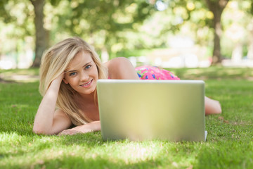 Beautiful blonde woman posing lying on a lawn