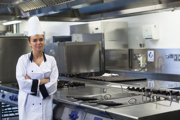 Young happy chef standing next to work surface arms crossed
