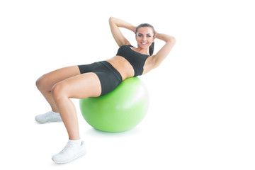 Fototapeta na wymiar Joyful fit woman doing an exercise on an exercise ball