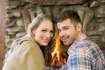 Smiling young couple in front of lit fireplace