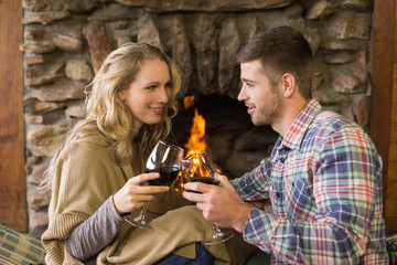 Couple toasting wineglasses in front of lit fireplace