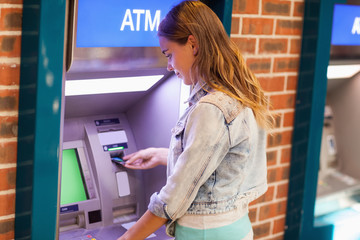 Pretty brunette student withdrawing cash