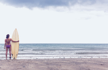 Fototapeta na wymiar Calm woman in bikini with surfboard on beach
