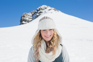 Fototapeta na wymiar Smiling woman in front of snowed hill and clear blue sky