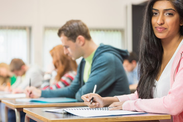 Fototapeta premium Female student with others writing notes in classroom