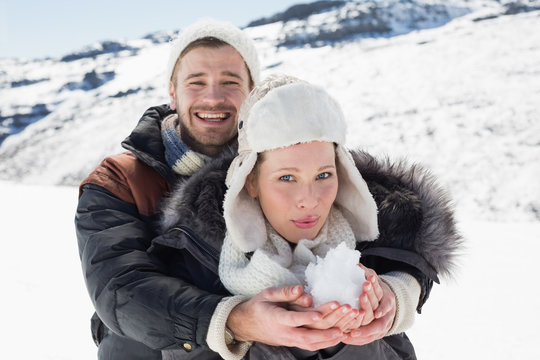 Couple with snow in hands on snow covered landscape
