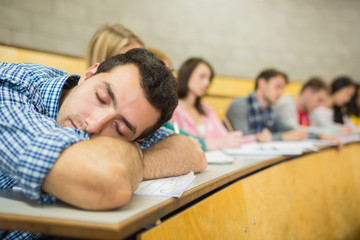 Male sleeping with students in lecture hall