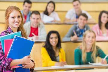 Smiling female with students sitting at the lecture hall