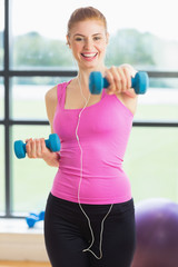 Fit woman exercising with dumbbells in fitness studio