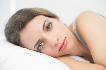 Fototapeta premium Serious brunette woman lying on her bed in the bedroom