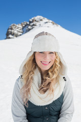 Fototapeta na wymiar Smiling woman in front of snowed hill and clear blue sky