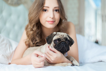Attractive young girl with dog while laying on bed