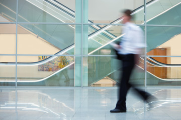 Businessman Walking Quickly down Hall in Office Building