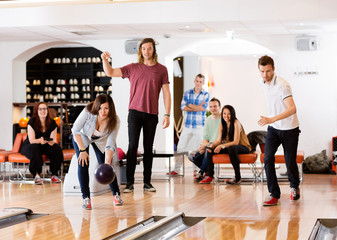 Man And Woman Bowling With Friends in Background