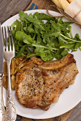 Roasted pork with apples and onions served with fresh arugula