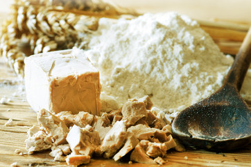 Hefe mit Mehl, Weizenähren und Kochlöffel