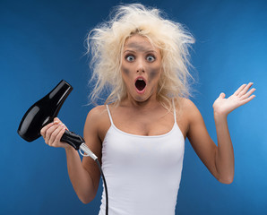 Funny blond girl having problem with hairdryer.