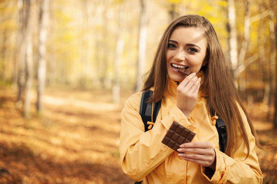 Happy young hiker woman eating chocolate