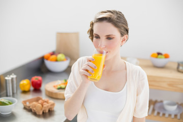 Lovely brunette woman drinking a glass of orange juice standing