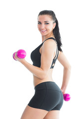 Fototapeta premium Portrait of smiling active woman training with pink dumbbells