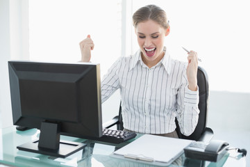 Happy chic businesswoman sitting at her desk in front of her com