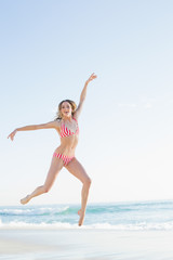 Obraz na płótnie Canvas Beautiful blonde woman jumping on the beach