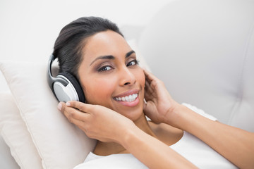 Content relaxing woman listening to music lying on couch