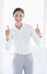 Smiling young business woman gesturing thumbs up