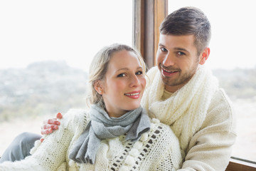 Couple in winter clothing against cabin window
