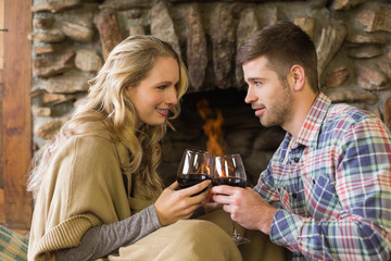 Couple toasting wineglasses in front of lit fireplace