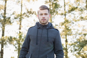 Young man in pullover standing in forest