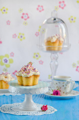 Vanilla cupcake with a rose on top of a blue wooden table