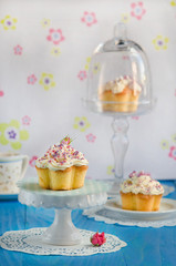 Vanilla cupcake with a rose on top of a blue wooden table