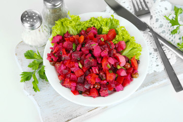 Beet salad on plate on napkin on wooden board isolated on white