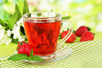 Delicious strawberry tea on table on bright background